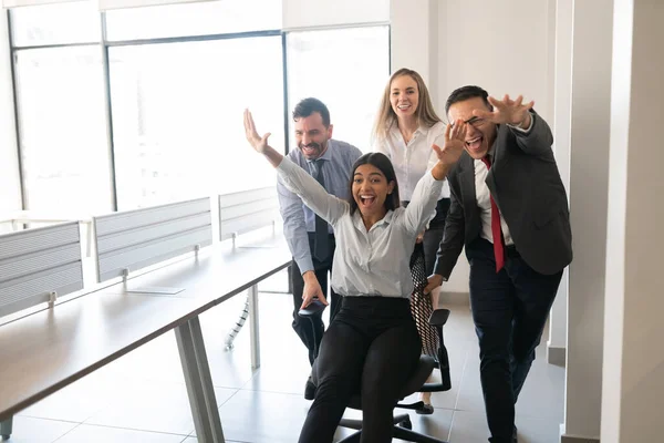 Игривая Бизнес Группа Толкает Коллегу Сидеть Кресле Веселиться Офисе — стоковое фото