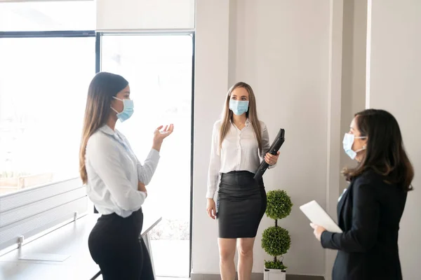 由三名戴口罩的女商人组成的小组在流感大流行期间举行了一次例行会议 — 图库照片