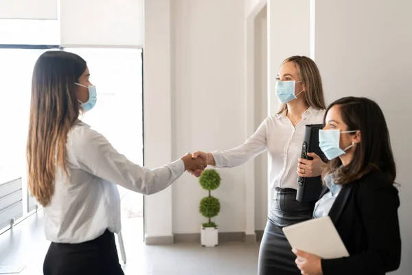 在大流行期间 戴防护面罩的商界人士在办公室握手 — 图库照片
