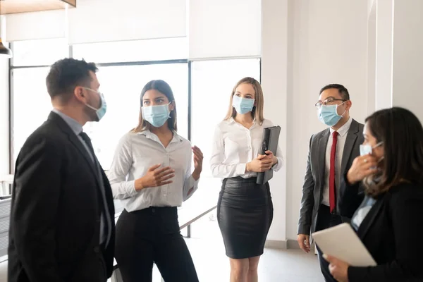 Group of business people wearing face masks having a standing meeting in office during pandemic