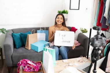 Çekici İspanyol sosyal medya etkileyicisi internetteki videolarını beğenmek ve abone olmak için eylem çağrısında bulunan bir işaret gösteriyor.