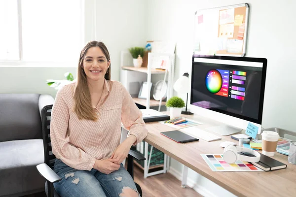 Portrait of a beautiful Caucasian graphic designer sitting in her office and smiling