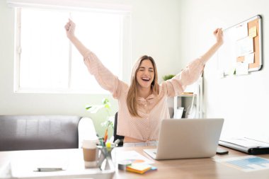 Başarılı ve çok heyecanlı bir kadın kollarını kaldırıyor ve aldığı güzel haberi kutluyor.