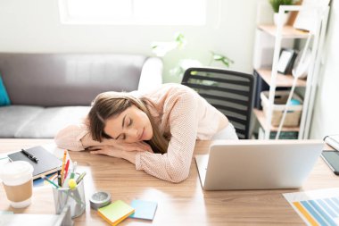 Çok çalışan iş kadını çok yorgun görünüyor ve çalışma saatleri boyunca ofis masasında uyuyakalıyor.