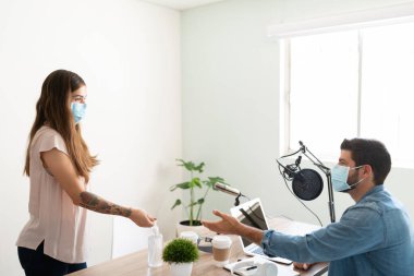 Canlı bir radyo programı için görüşmeye gelirken el dezenfektanı kullanan hoş bir bayan sanatçı ve konuk.