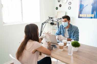 Blog yazarı ve podcast sunucusu bir online şov sırasında maske ve eldiven takarken konuk sanatçıyla röportaj yapıyor
