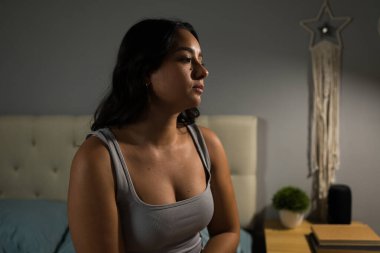 Mutsuz bir kadın, loş bir yatak odasında, yatakta oturuyor. Acı dolu bir ayrılıktan sonra, ilişki sorunlarını ve yalnızlık hislerini yansıtıyor.