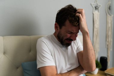 Ağlayan adam yatakta oturuyor ve ayrılıktan sonra kalp kırıklığı yaşıyor. İlişki sorunları ve duygusal acıdan muzdarip.