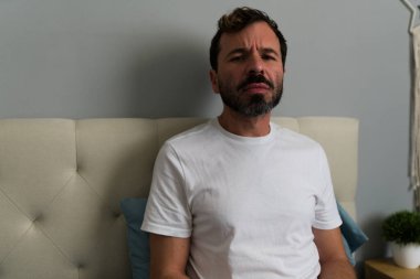 İlişkiden ayrıldıktan sonra yatakta oturan bir adamın portresi. Yatak odasında kalp kırıklığı ve yalnızlık yaşıyor.