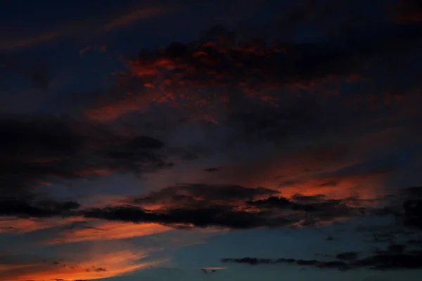 Grey storm clouds with red clouds against a blue sky during sunset — Stock Photo, Image