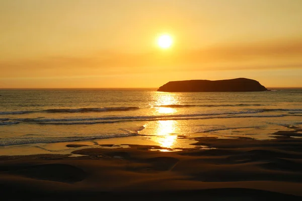 Red gold. Rays of the rising sun over the ocean. Sandy beach has orange color.