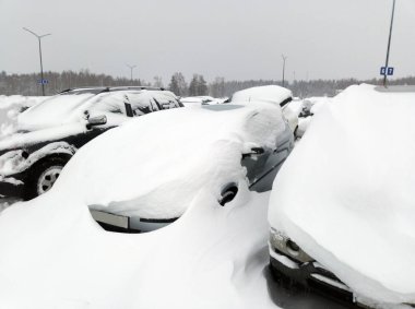 Kar yağışı sırasında konut alanındaki bir otoparkta karla kaplı arabalar