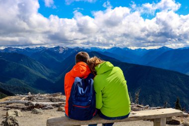 Sevgi dolu bir çift bir bankta oturuyor ve dağlara bakıyor..