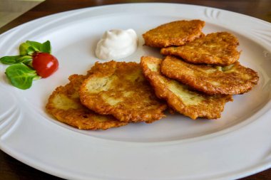 Beyaz bir tabak, geleneksel bir tabak üzerinde ekşi krema ile Patates gözleme dranik.