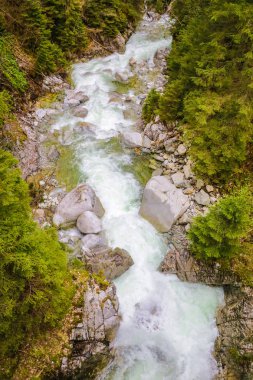 Islak kayalar ve çakıl shore ile dağ nehir rapids tepeden dron görünümü.