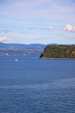 Sahilin yeşilliklerle kaplı kayalık kısmı denizle çevrilidir.