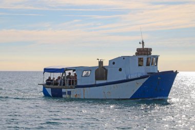 İnsanlar eski bir tekneyle denize açılıyorlar. Su sınırlarının ihlali