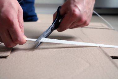 Adam mobilyaları monte etmek için kravatı kesiyor.