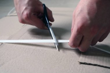 Bir adam, mobilyaları monte etmek için karton kesmek için makas kullanıyor.