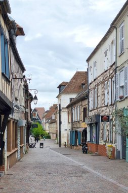 Rouen, Fransa, 27 Temmuz 2025, tarihi yarı ahşap binalarla çevrili bir Fransız köyündeki antika kaldırım taşı caddesi. Yerleşim bulutlu bir gökyüzü altında barışçıl, eski dünya cazibesi yayar. Seyahat ve kültürel keşif temaları için idealdir..