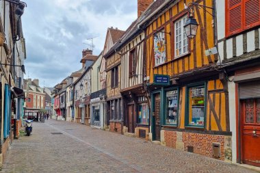 Rouen, Fransa, 27 Temmuz 2025: Çekici Avrupa köyü caddesi yarım keresteli büyüleyici binalarla çevrili. Bulutlu bir gökyüzünün altındaki kaldırım taşı yolu, canlı cephelerle ve klasik mimari detaylarla, kültürel mirası ve tarihi yansıtıyor..