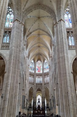 Rouen, Fransa, 27 Temmuz 2025: Yükselen tavan, karmaşık şekilde oyulmuş sütunlar ve canlı vitray pencerelerin yer aldığı gotik bir katedralin görkemli iç mekanı. Mimari etkileyici detaylar sergiliyor, dingin ve ruhani bir ortam yaratıyor.