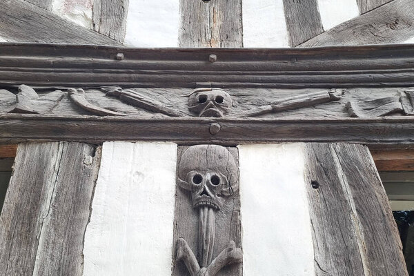 Rouen, France, July 28, 2025: Close-up of a medieval timber-framed structure featuring intricately carved wooden skulls. the rustic wood and traditional craftsmanship highlight historical architectural design, offering a unique look into past
