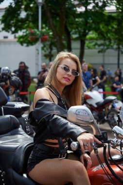 Genç seksi kadın bir motosiklet üzerinde oturuyor. Güzel kız bir motosiklet üzerinde pozlar.