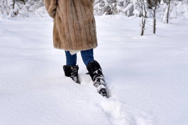Kış botları içinde bir kadın karda koşar..