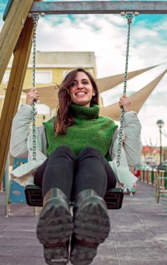 Sallanan oynarken mutlu çekici İspanyol kadın portresi. Hippi tarzı. Sallanan ve gülümseyen sevimli uzun saçlı kız.