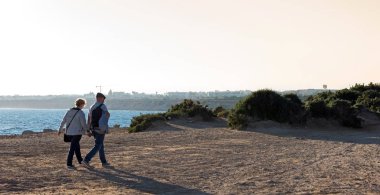 Orrevieja, İspanya - 05 Ocak 2019: ellerini tutarken deniz kıyısı yürüme çift.