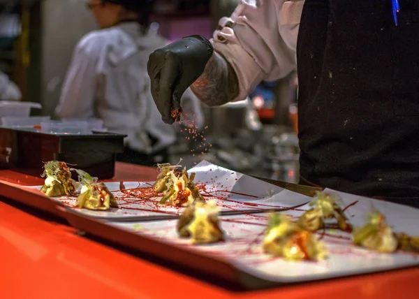 Hands cooking gourmet dish. Pekinese dumplings of ear's pig served with hoisin sauce and citrus barbecued marlin.