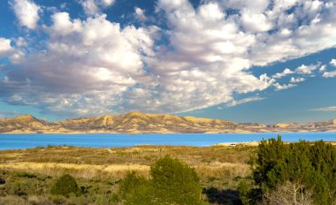 Evler, bitkiler ve dağlarla çevrili güzel bir göle bakan manzara..