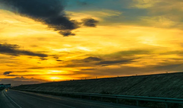 Belo pôr do sol com nuvens sobre a estrada à noite — Fotografia de Stock