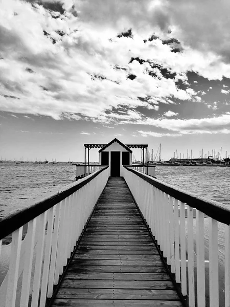 Muelle en la playa contra el cielo nublado y el puerto . —  Fotos de Stock