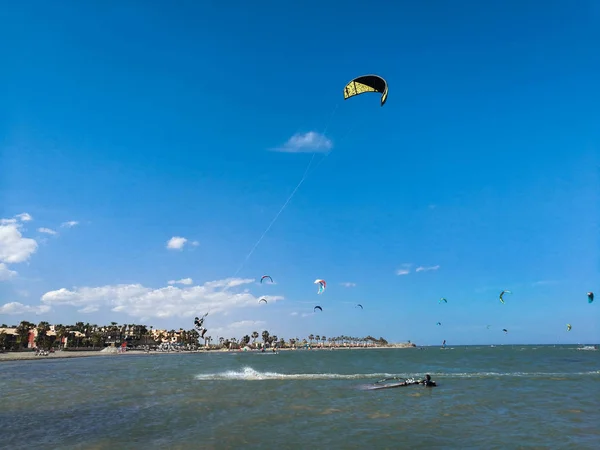 Kite boarding desportista voando alto com pipa e kiteboard em botas no céu azul, esportes ativos e estilo de vida na costa espanhola . — Fotografia de Stock