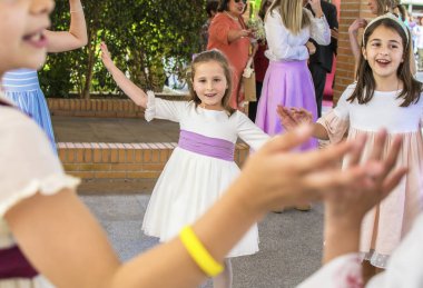 Güzel elbiseler üzerinde küçük kızlar eğlenmek ve birlikte açık havada atlama oynamak. Gün ışığında özel kutlama.