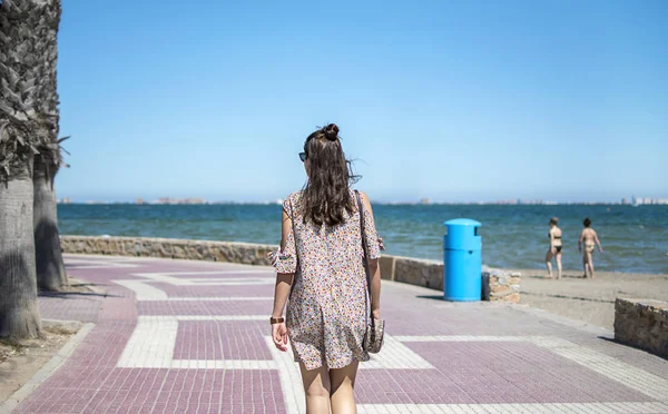 Mujer joven y feliz vistiendo vestido casual caminando por la playa . —  Fotos de Stock