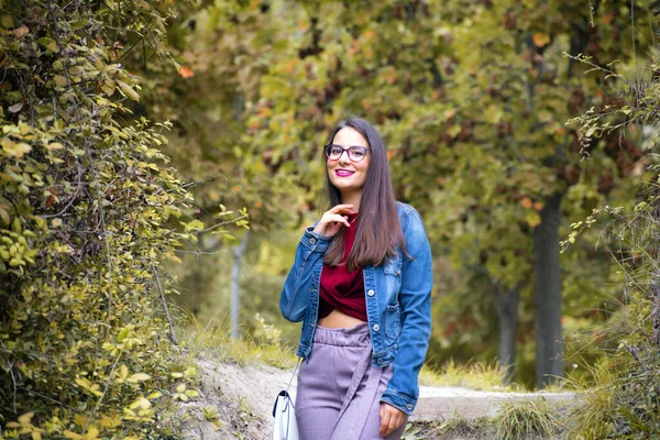 Porträt einer attraktiven jungen Frau, die im Herbst in einem Park mit der Kamera flirtet. — Stockfoto