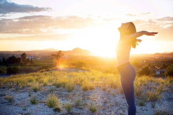Młoda dziewczyna z otwartymi ramionami swobodnie na szczycie góry przed zachodem słońca w Murcji, Hiszpania. Spacerując i ciesząc się wolnością na wsi. Atrakcyjne dopasowanie zdrowa kobieta na polu trawy uśmiechnięta w powietrzu. — Zdjęcie stockowe