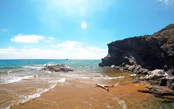 Ein Mann liegt am Meer am idyllischen spanischen Strand und entspannt sich an einer tropischen Küste mit türkisfarbenem Wasser — Stockfoto