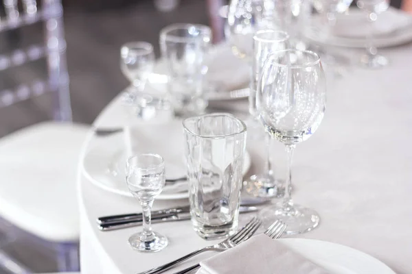 stock image Wine glasses are on the table on a white tablecloth.  The table is set for the holiday. White napkins on the plates