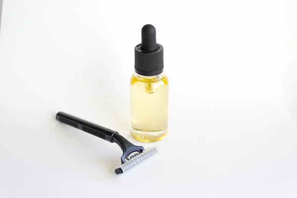 Disposable black razor and dropper glass bottle with essential oil.
