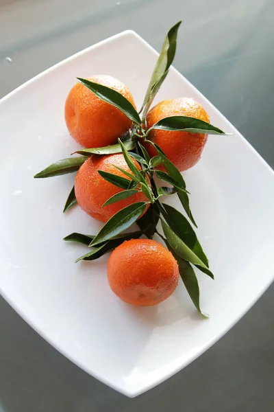 Ripe orange mandarin on a white square plate. Ripe tangerin with leaves — Stock Photo, Image