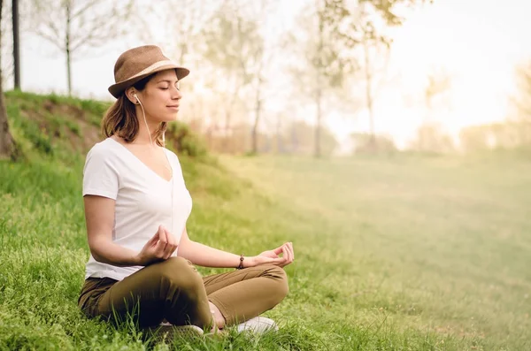 Doğada müzik dinlerken sabah Meditasyon genç güzel kadın. Güneş doğuyor, Güneş ışınları alanında. Rehberli meditasyon. 