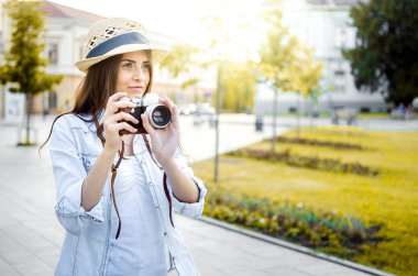 Gün batımında kentin eski bir retro kamera ile şapka alarak resim giyen güzel kız