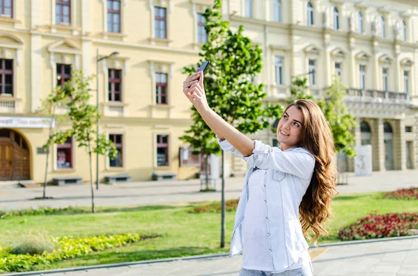 Güzel genç esmer gülümseyen selfi kasabada alarak uzun saçlı