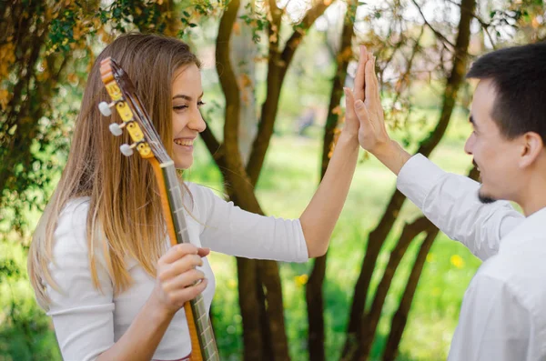 Young male guitar teacher giving high five to his female student after guitar class in the park