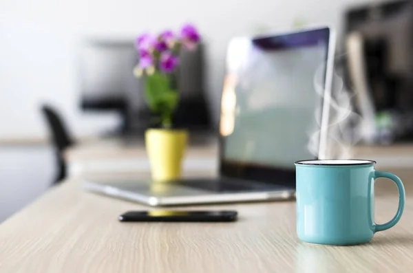 Morgon på kontoret. Laptop öppen, mobiltelefon och en kopp — Stockfoto