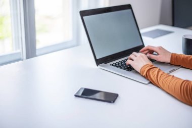 Pencerenin yanında dizüstü bilgisayarda yazan kadın ellerinin kapatılması